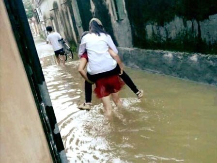 Nữ sinh để bố khiêng xe đạp, mẹ cõng qua đoạn đường ngập bị chỉ trích