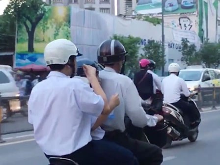 Học sinh vừa đi đường vừa xúc cơm ăn ngay trên xe máy