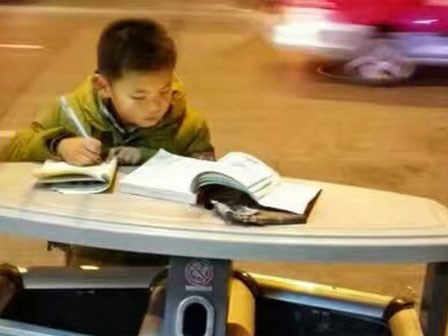 Hình ảnh cậu bé học bài trên thùng rác cạnh xe khoai lang nướng của mẹ gây xúc động mạnh