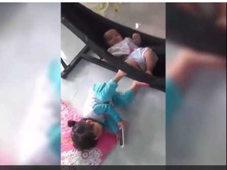 Hình ảnh bé gái vừa xem điện thoại vừa đạp võng .. ru em gây nhiều tranh cãi