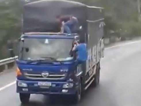 Hai người đàn ông đánh đu trên đầu xe tải