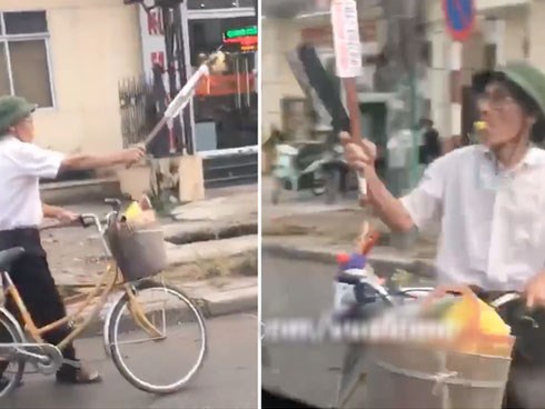 Cụ ông cầm gậy và dao phay đồng thời thổi còi inh ỏi để sang đường cho chắc