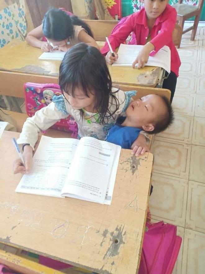 Vừa bế em vừa học bài, tấm hình chụp cô bé tiểu học khiến nhiều người xót xa-1