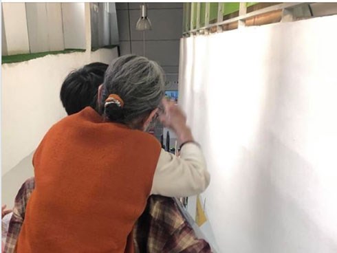 Hình ảnh chàng trai trẻ cõng bà đi cầu thang máy cùng lời hỏi thăm