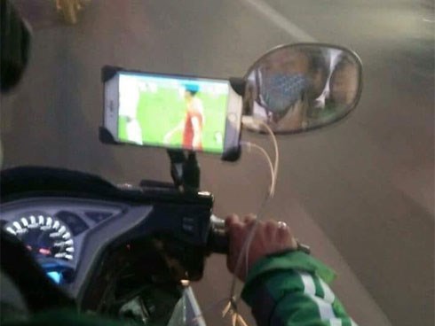 Vừa lái xe vừa dùng điện thoại xem Việt Nam đá, tài xế xe ôm khiến nhiều người lo lắng