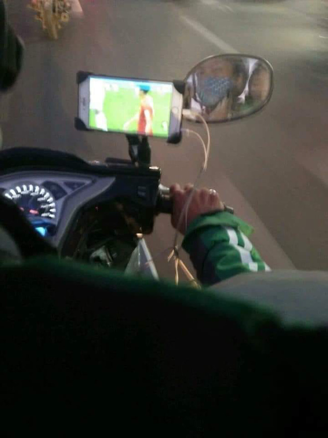 Vừa lái xe vừa dùng điện thoại xem Việt Nam đá, tài xế xe ôm khiến nhiều người lo lắng-1