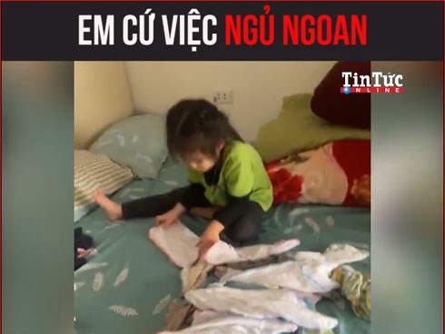 Cô bé giúp mẹ vừa trông em, vừa gấp đồ