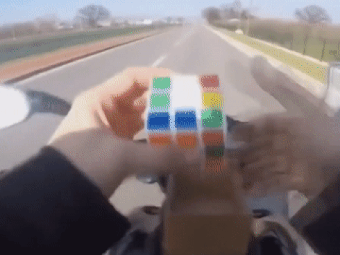 Tài xế vừa phóng xe máy vừa chơi rubik