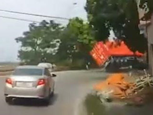 Xe máy thoát chết gang tấc khi container lật nhào