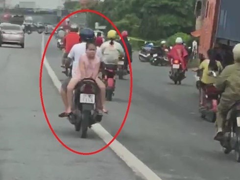Bố chở con ngồi ngược trên xe máy chạy bon bon trên đường