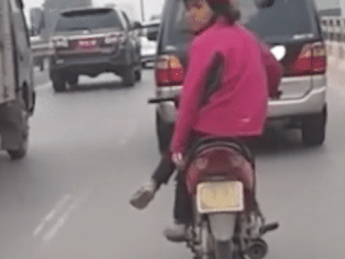 Người phụ nữ vắt chéo chân, lạng lách khi đi xe máy trên phố