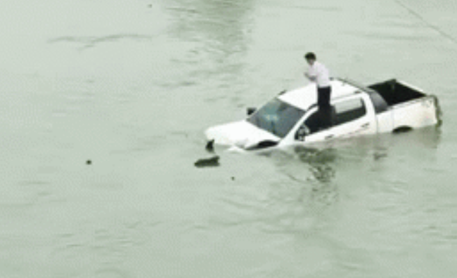 Hình ảnh tài xế trèo lên nóc xe ô tô trôi lềnh bềnh giữa sông khiến nhiều người hoang mang-1