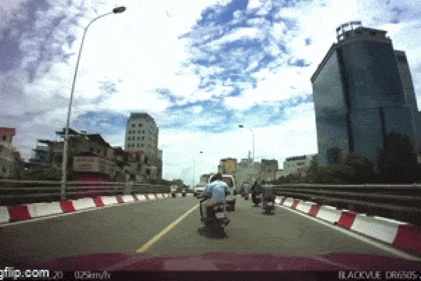 Người đàn ông ngồi trên đầu xe ô tô đang chạy trên đường-1