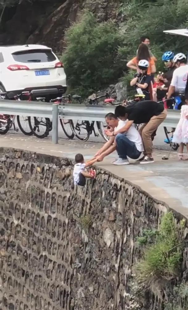 Rùng mình khoảnh khắc người đàn ông nắm tay đứa trẻ đang lơ lửng bên mép đường, bức xúc hơn cả là việc làm của người còn lại-1