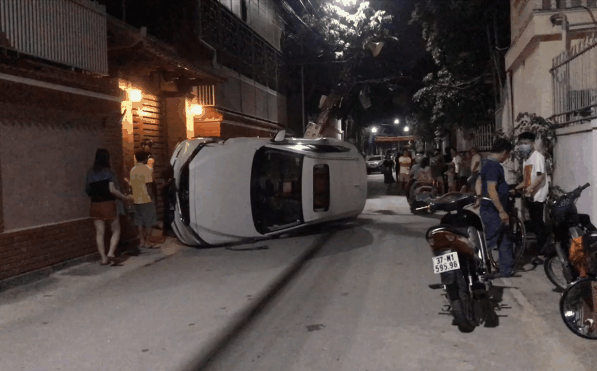 Xế hộp đâm gãy cột điện rồi lật nghiêng giữa đường, người trong xe bò ra từ cửa sổ trời-1