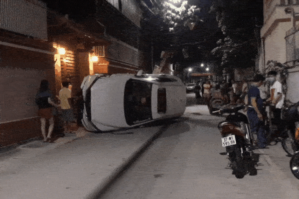 Xế hộp đâm gãy cột điện rồi lật nghiêng giữa đường, người trong xe bò ra từ cửa sổ trời