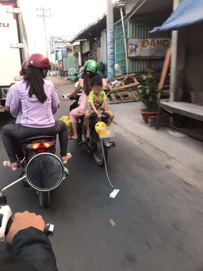 Mẹ để con trai ngồi ngược sau yên xe máy chơi đùa khi đi đường, mặc kệ xe tải chạy sát vách gây phẫn nộ-1