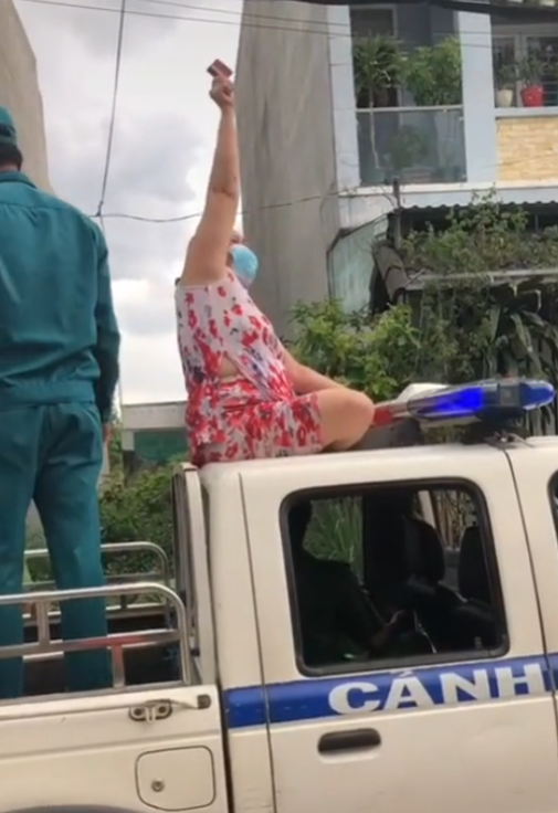 Không đeo khẩu trang, người phụ nữ còn trèo lên nóc xe cảnh sát ngồi, múa may làm loạn nơi công cộng-1
