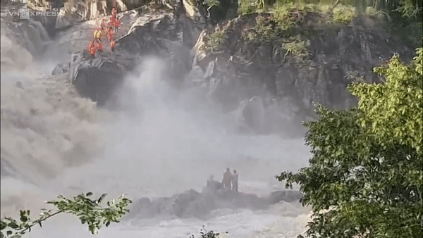 Kinh hãi: 3 người mắc kẹt trên mỏm đá giữa dòng lũ dữ chỉ chực cuốn phăng mọi thứ-1