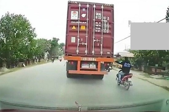 Nam thanh niên liều lĩnh bám vào đuôi container khi đang đi xe máy