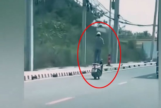 Tài xế liều lĩnh đứng trên yên xe đang chạy