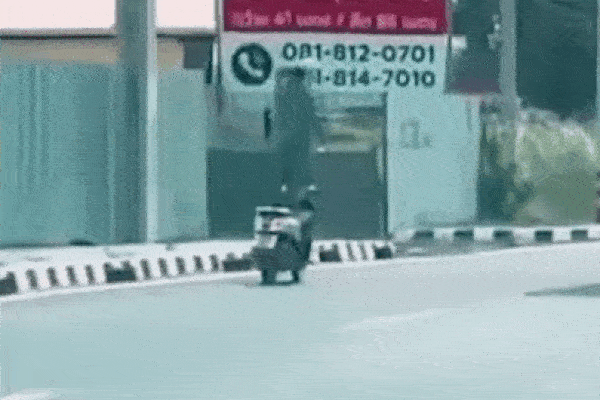Người đàn ông đứng trên yên xe máy, chạy bon bon trên đường