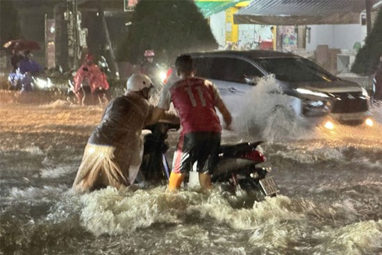 Mưa lớn kéo dài, người dân Đồng Nai ‘vác xe’ qua dải phân cách để thoát ngập